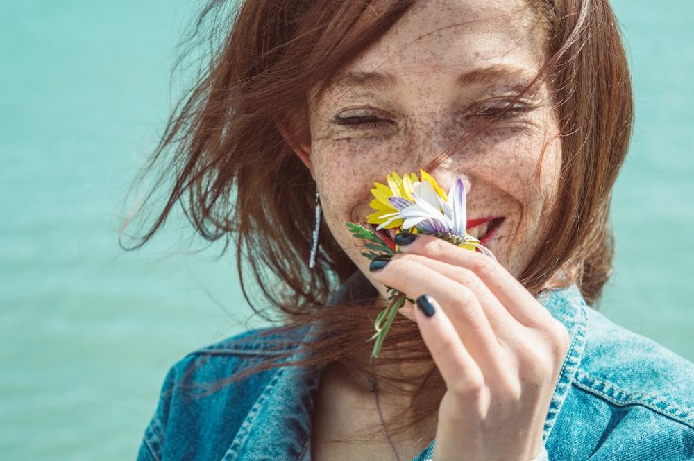 portrait photography of woman sniffing flower