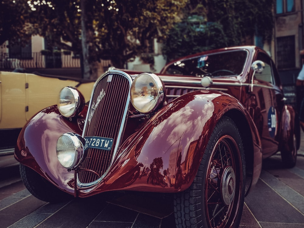 Auto rossa classica parcheggiata accanto al veicolo giallo