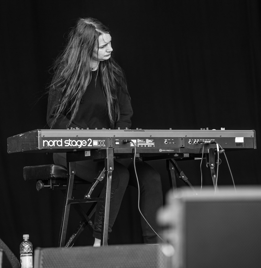 grayscale photo of woman playing electric keybaord