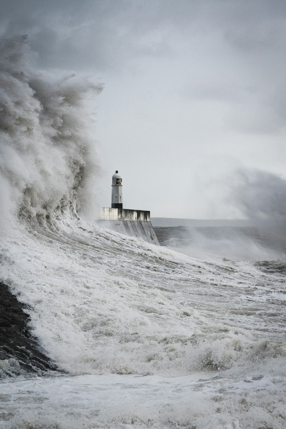 um farol cercado por uma enorme onda no oceano