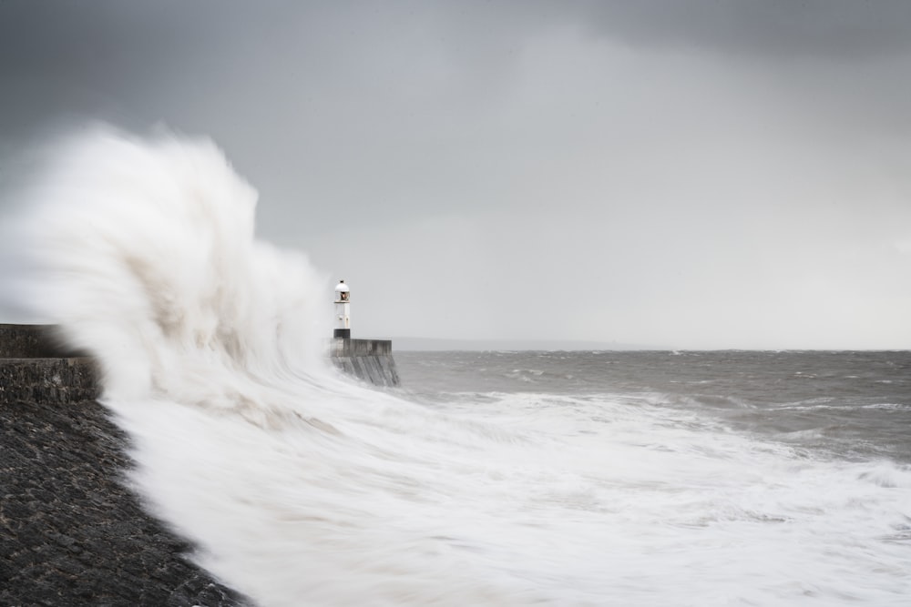 uma grande onda atingindo um farol em um dia de tempestade