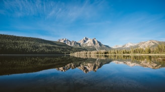 A serene mountain lodge surrounded by snow-capped peaks under a clear blue sky.