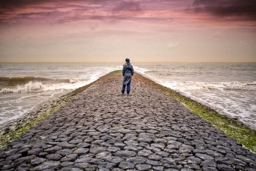 person standing on pathway between body of waters