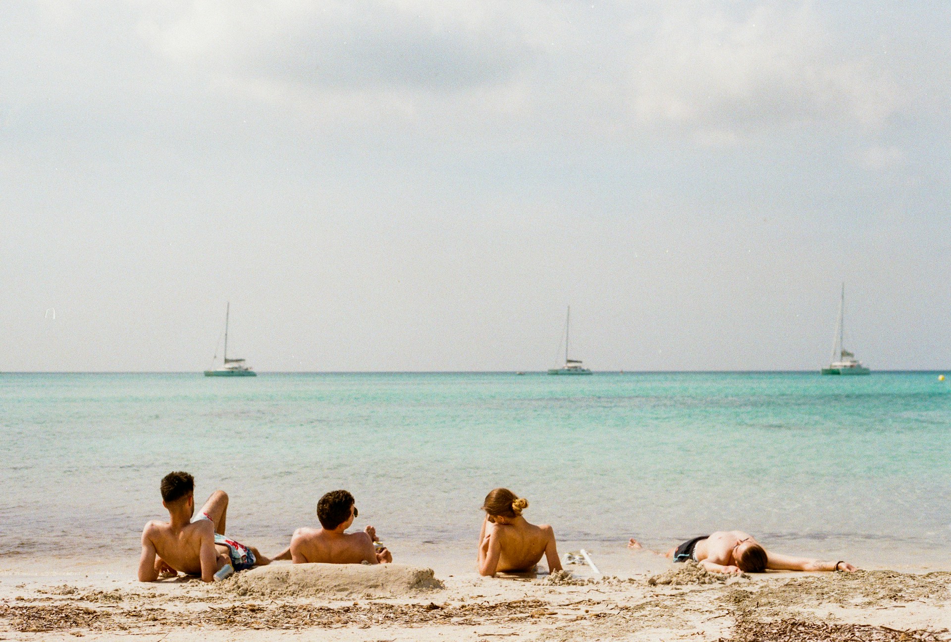 four person lying on beach