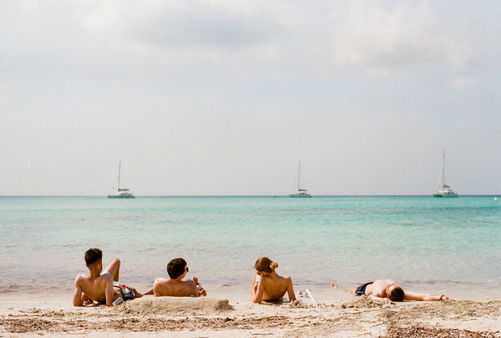 four person lying on beach