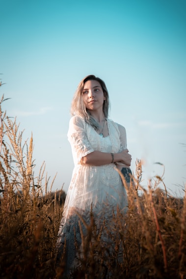 A sunlit meadow with a model wearing a flowing bohemian summer dress, barefoot and carefree.