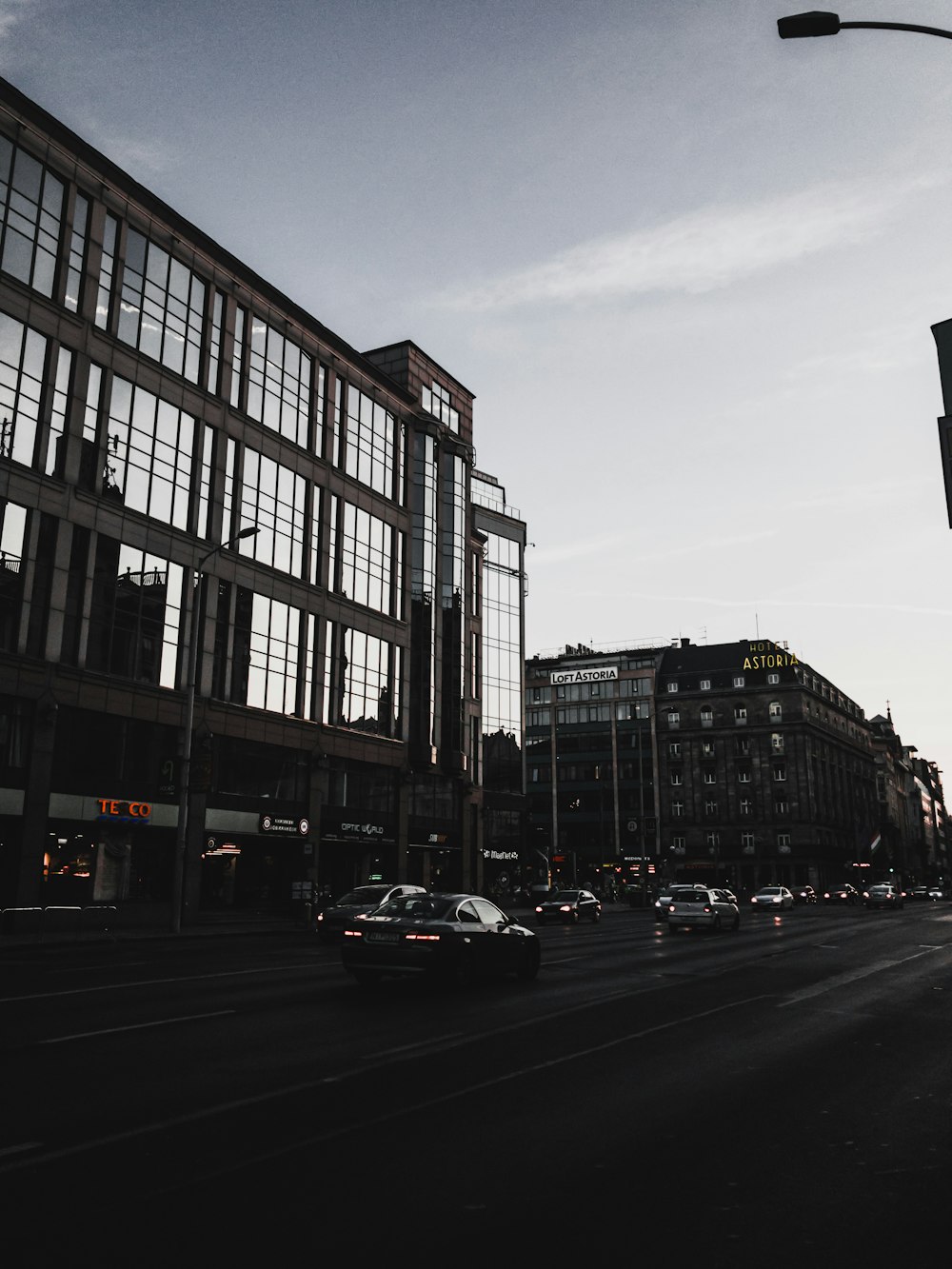 greyscale photo of vehicles on road beside buildings