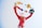 A colorful clown statue with a striped red suit is juggling objects, including a hamburger and other abstract shapes. The clown has a playful pose with arms raised high.