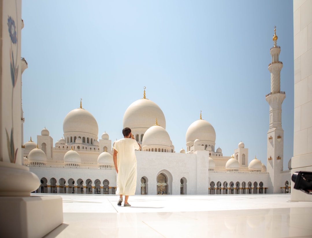 man standing near white mosque, A wide shot of a person wearing white thawb standing at Sheikh Zayed Grand Mosque Center