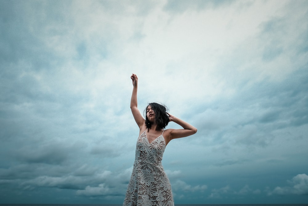 woman wearing white floral dress raising right hand