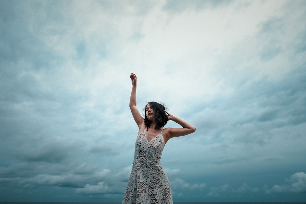 Mujer con vestido floral blanco levantando la mano derecha