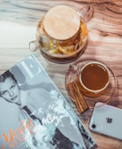 An inviting scene with a cup of tea on a marble countertop, next to a stack of fashion magazines and a silk handkerchief.