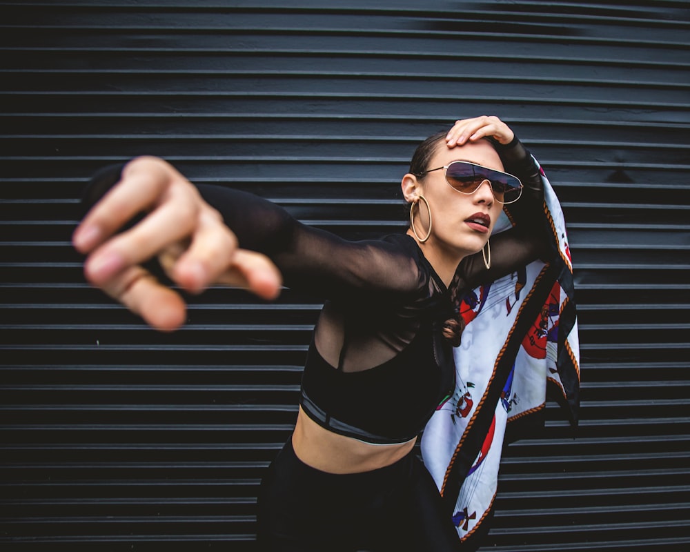 woman wearing black long-sleeved crop top standing beside black roll-up door