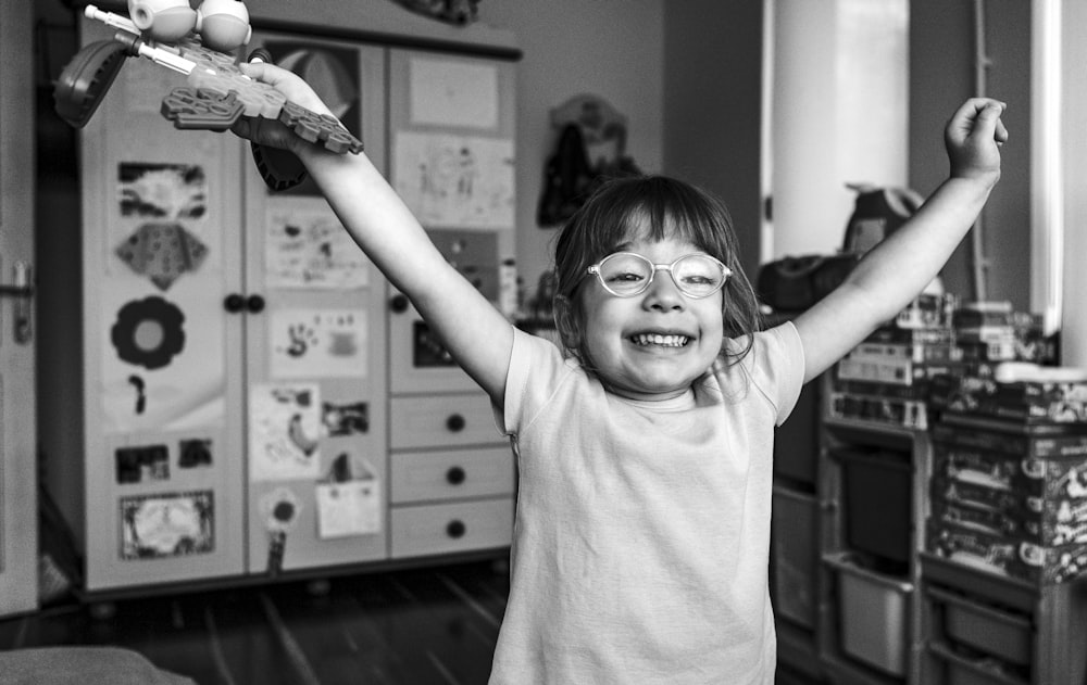 grayscale photography of girl raising both hands smiling