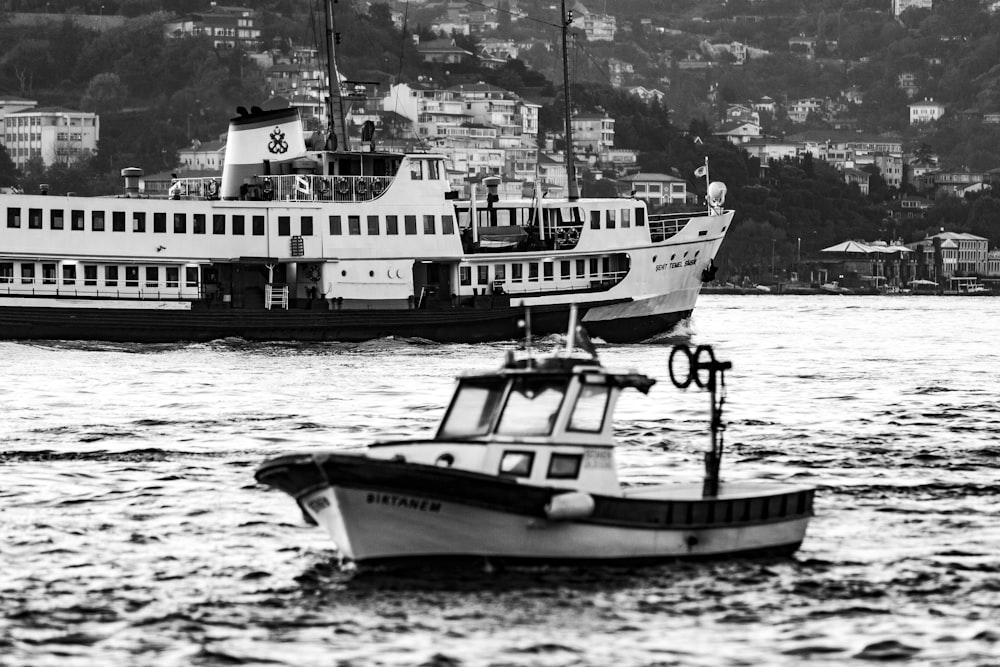grayscale photo of boat and cruise ship on body of water