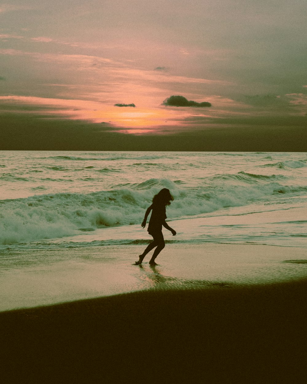 silhouette of woman on seashore during golden hour