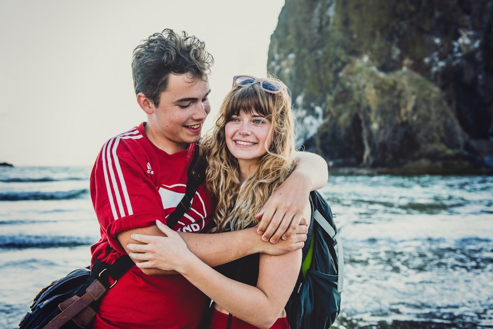 man and woman hugging near rock during daytime