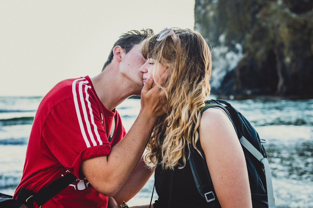 man kissing woman in black top