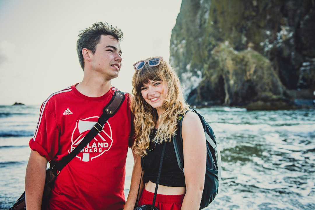 man in red wearing shirt beside of woman in black top