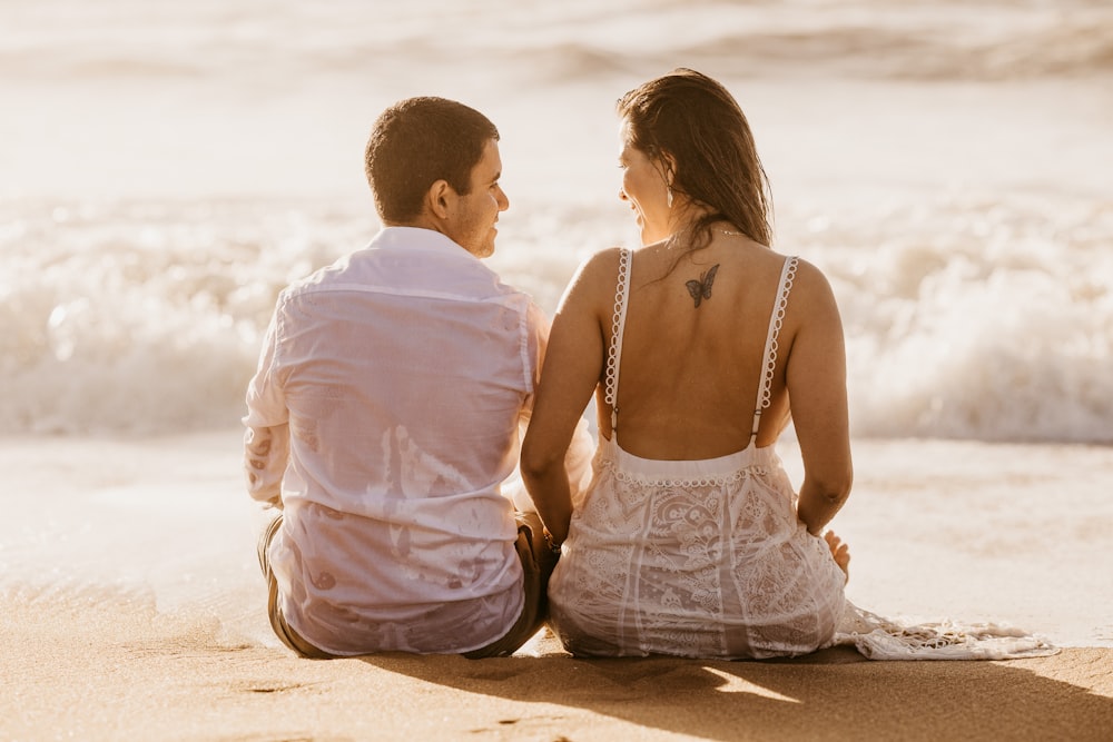 sitting man and woman on seashore looking at each other