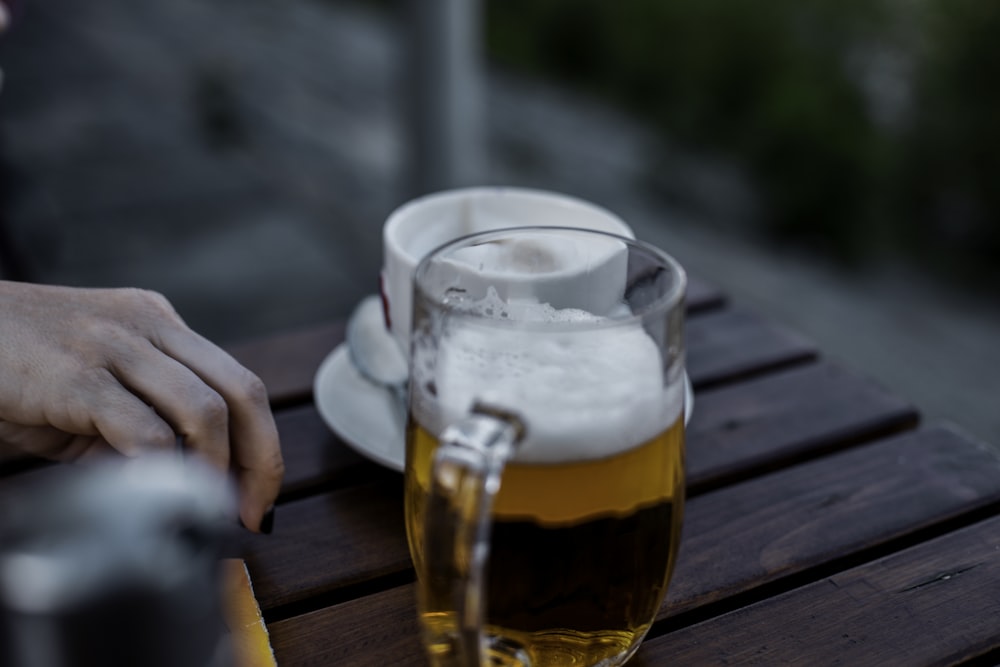 filled clear glass mug on gray wooden table