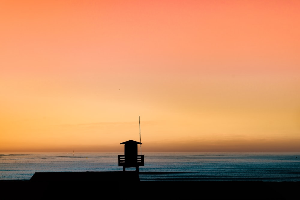 ゴールデンアワーの海沿いのコテージのシルエット写真