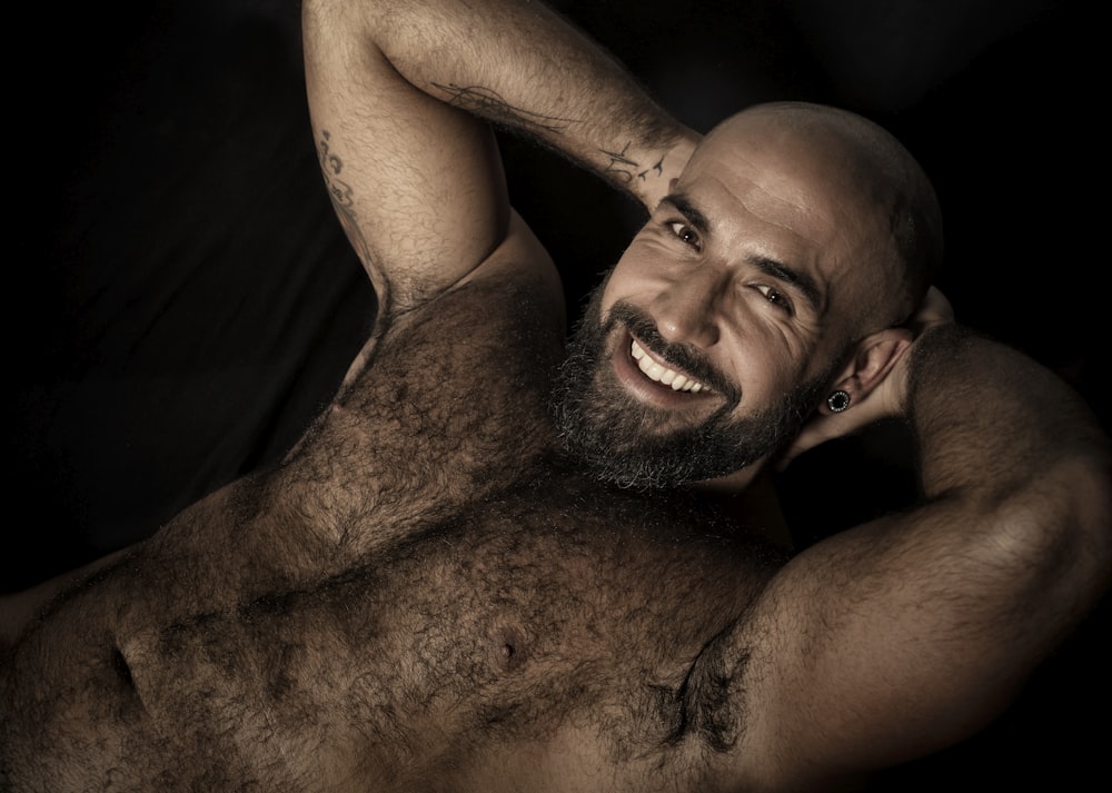 topless man smiling while touching his head