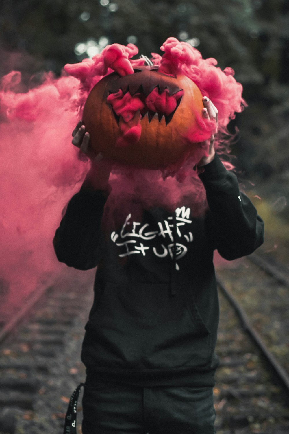 standing person in black hoodie holding red smoke bomb