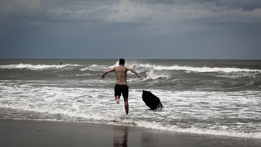 topless man running going on sea during daytime