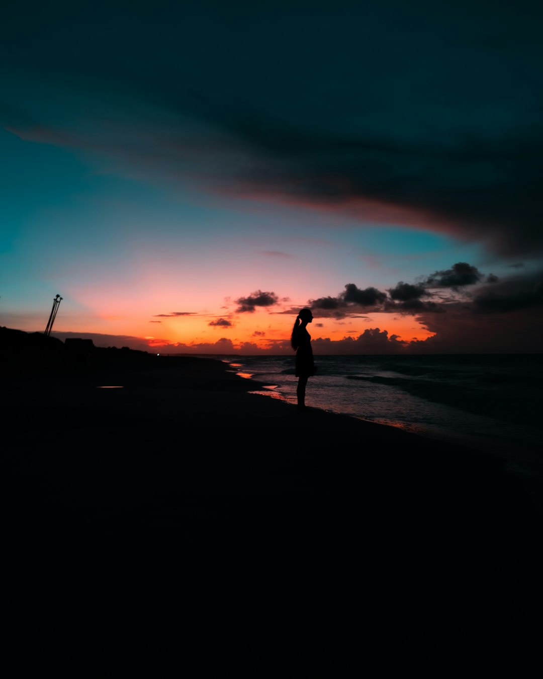 woman standing on shore facing the sea during day