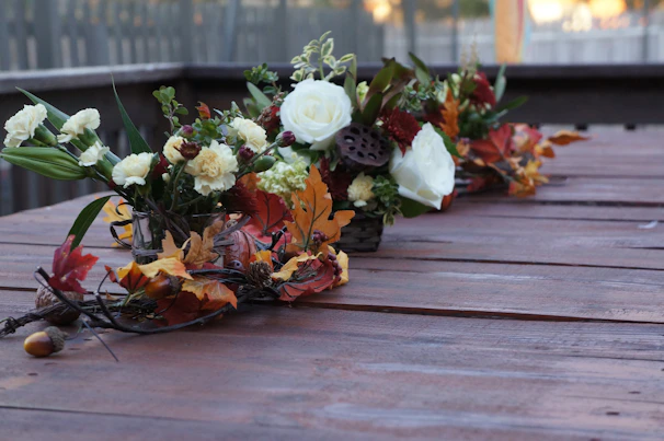Artful arrangement of seasonal flowers on a rustic wooden table bathed in warm natural light.