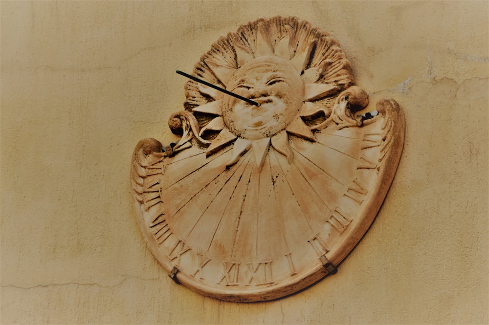 brown concrete sun-like clock on wall