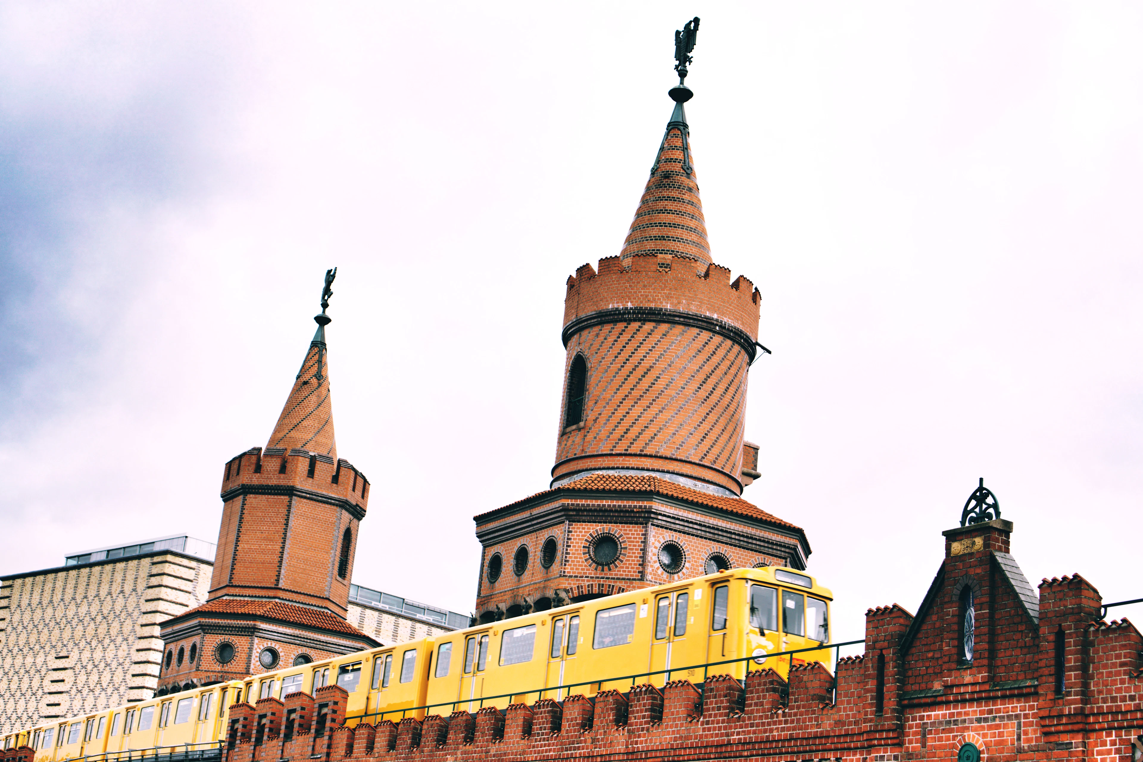 A yellow Berlin U-Bahn train crossing the red-brick Oberbaum Bridge between its two neo-Gothic turrets