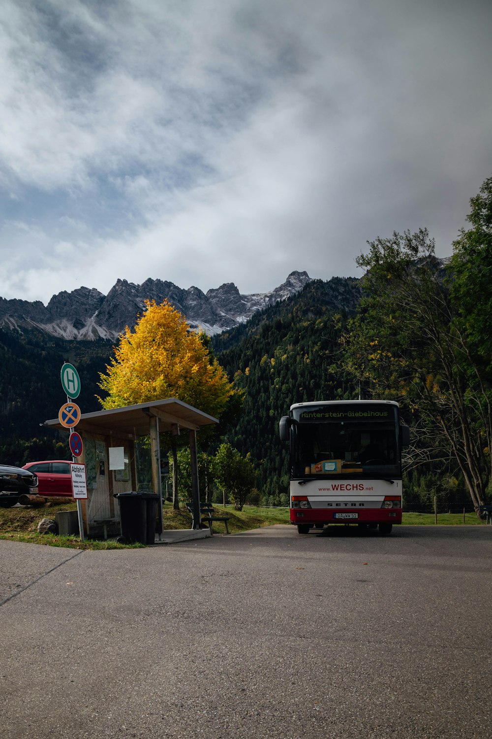 white and red bus near waiting shed