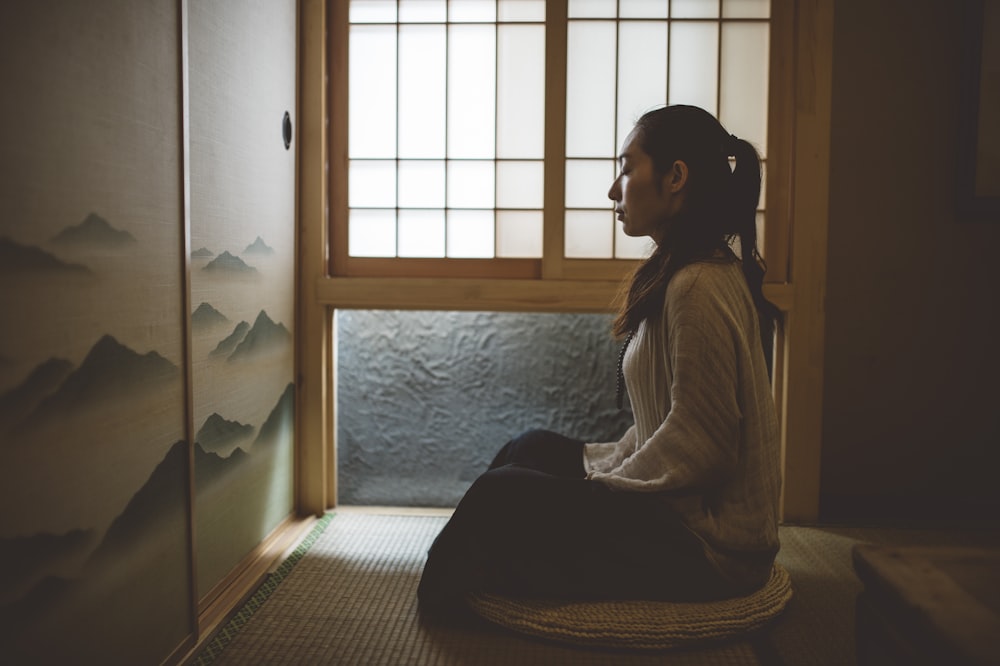 woman sitting on floor near window