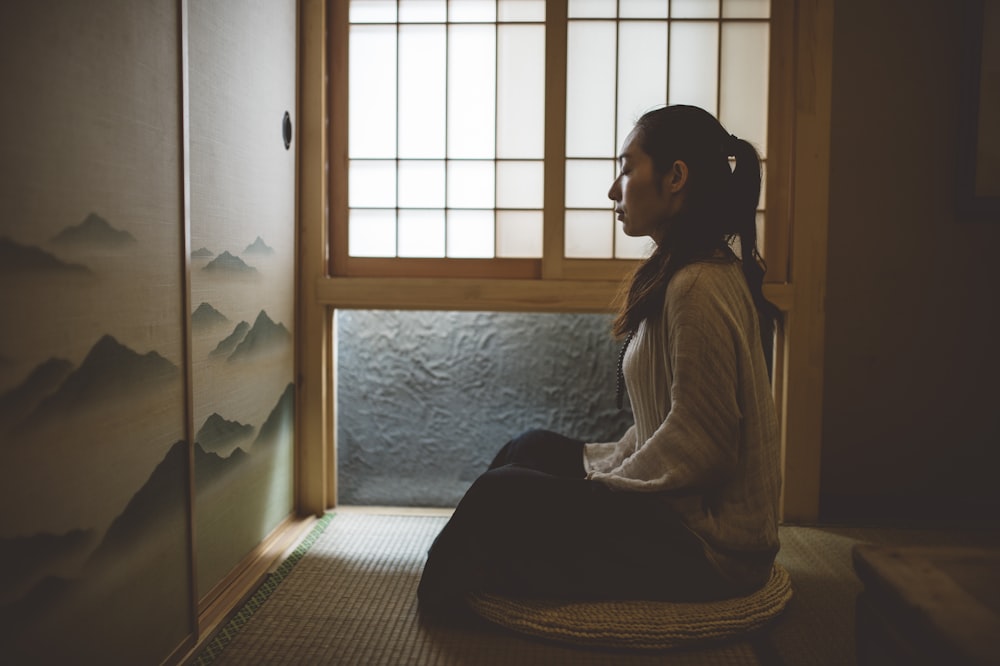 donna seduta sul pavimento vicino alla finestra