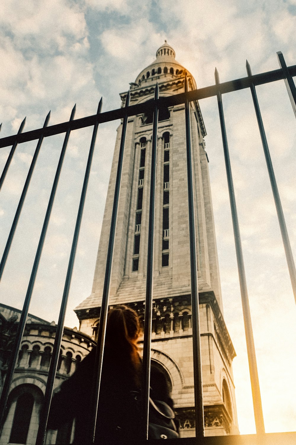 a tall building with a clock tower behind a fence