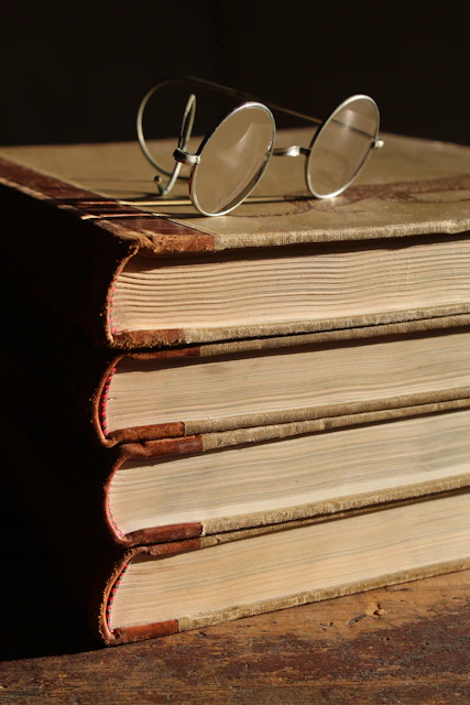 gafas de marco redondo pequeño sobre una pila de libros