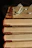 A stack of well-loved books with a pair of reading glasses on top.