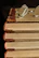 A stack of well-loved books with a pair of reading glasses on top.