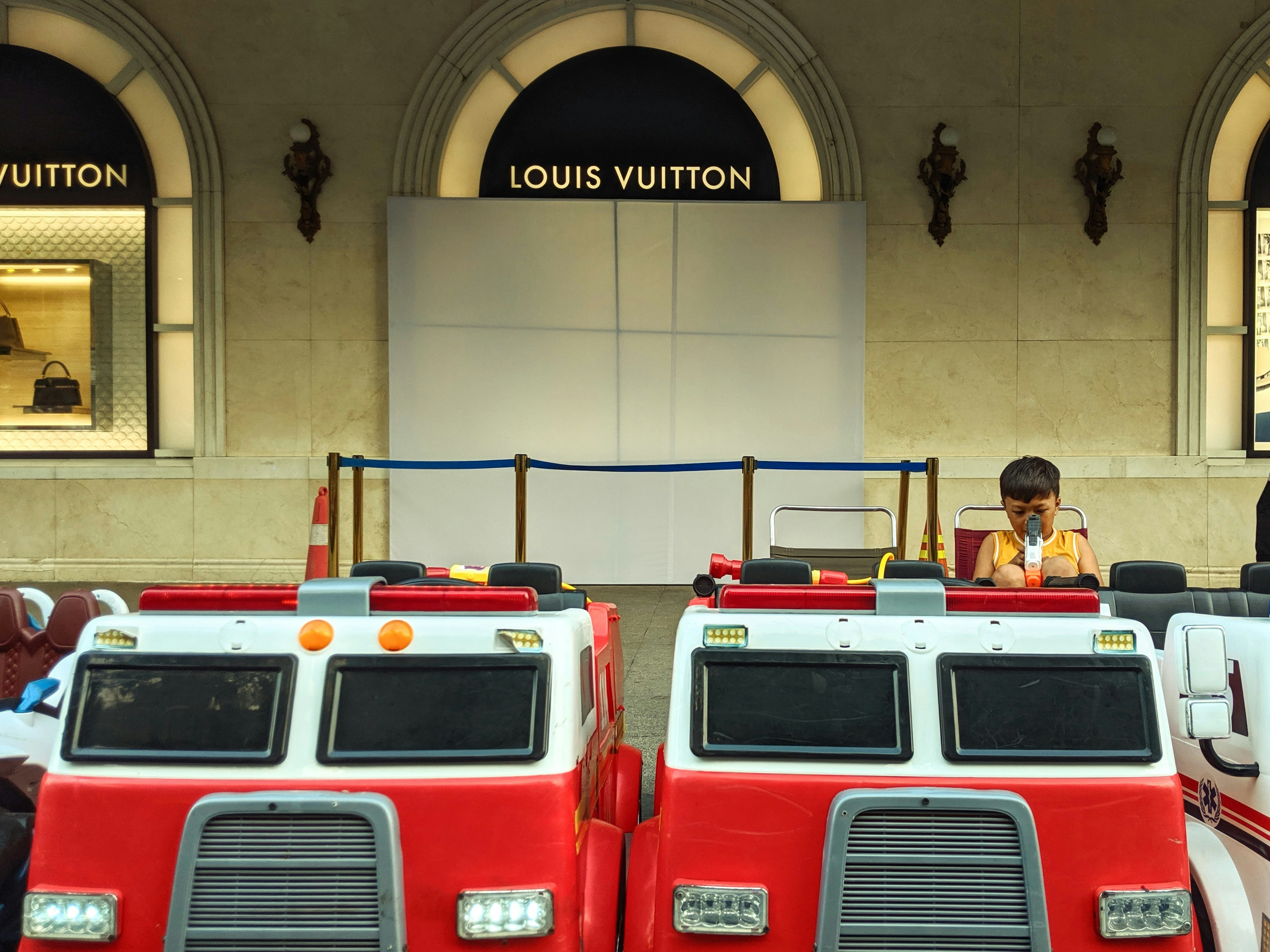 Kid on a toy car near a luxury store