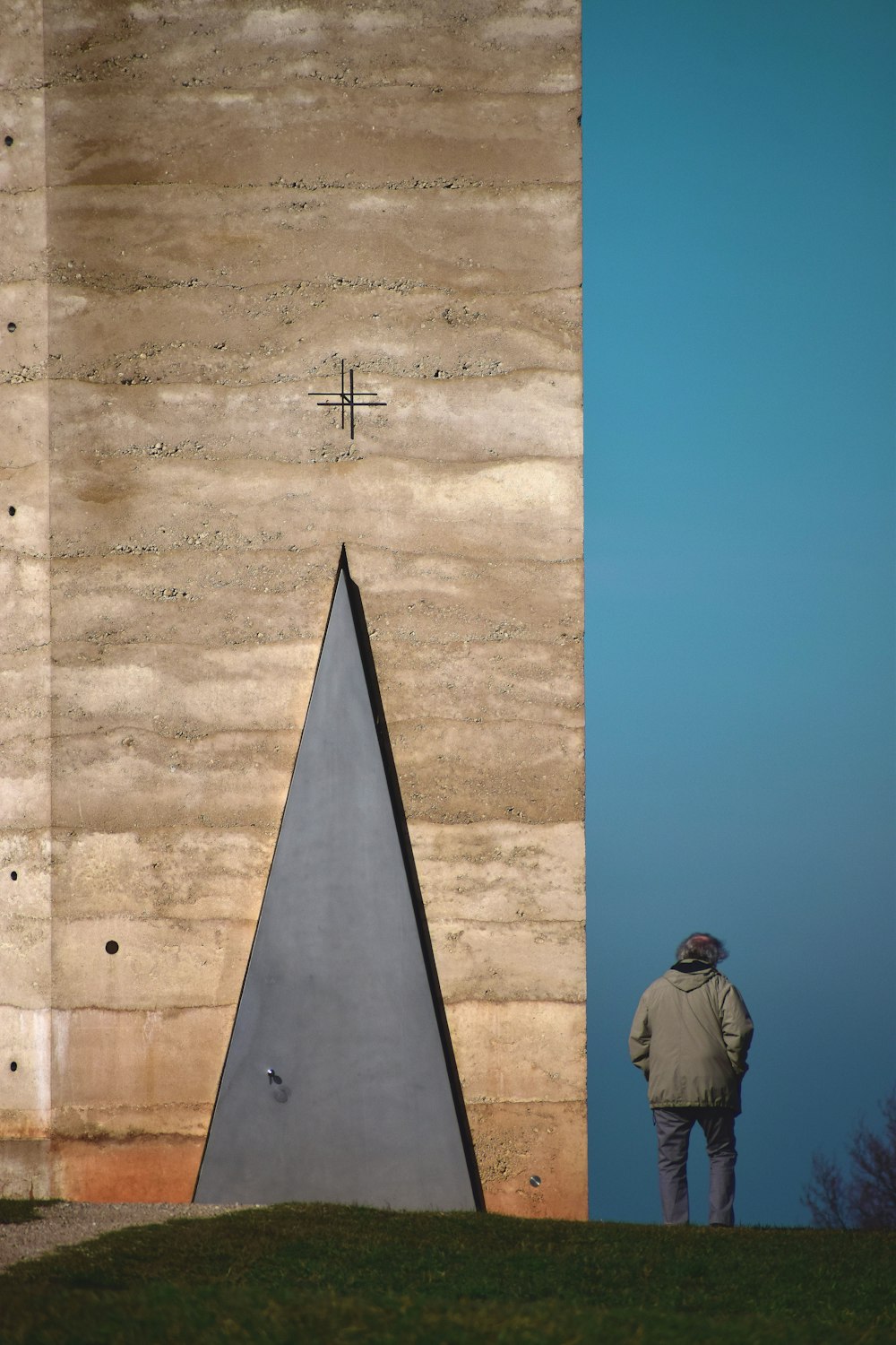 person wearing white hooded jacket standing near concrete wall