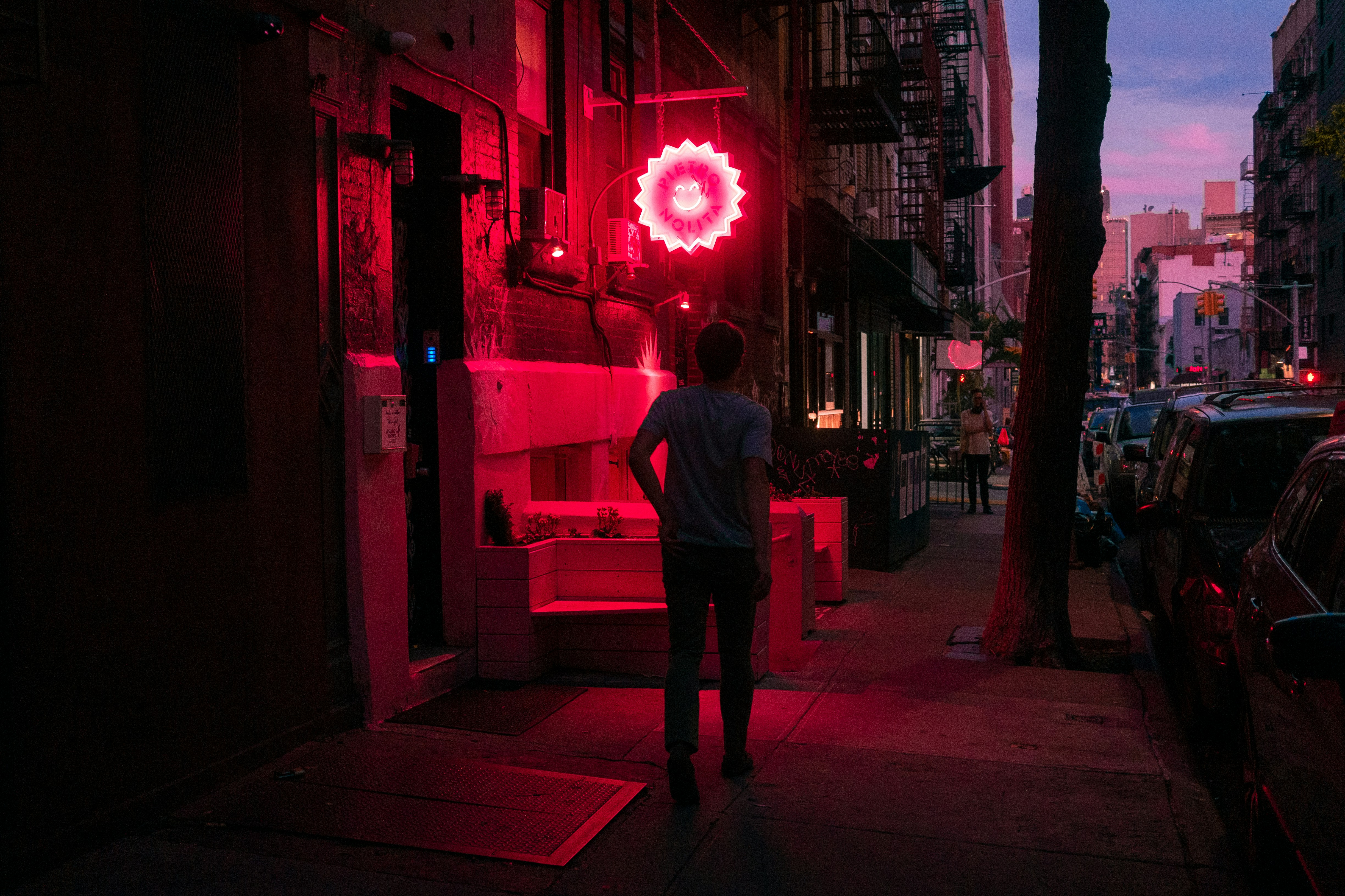 people walking on pathway near buildings and different vehicles on road during night time