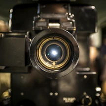 A sleek black and white close-up of a vintage film camera lens reflecting light.