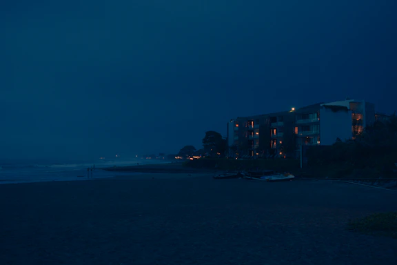 Cozy seaside view of Teti Appartments at sunset with warm lights glowing from windows