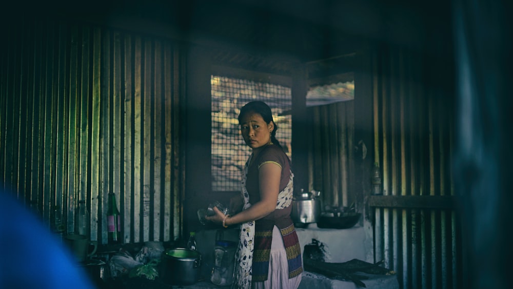 woman in apron standing near cooking pots