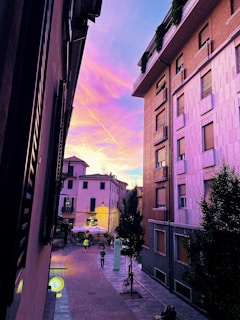 A vibrant street scene at sunset with people walking and colorful buildings