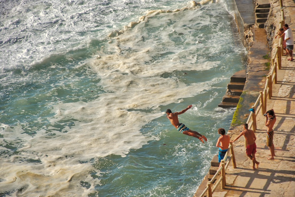 man jumping on sea on focus photography