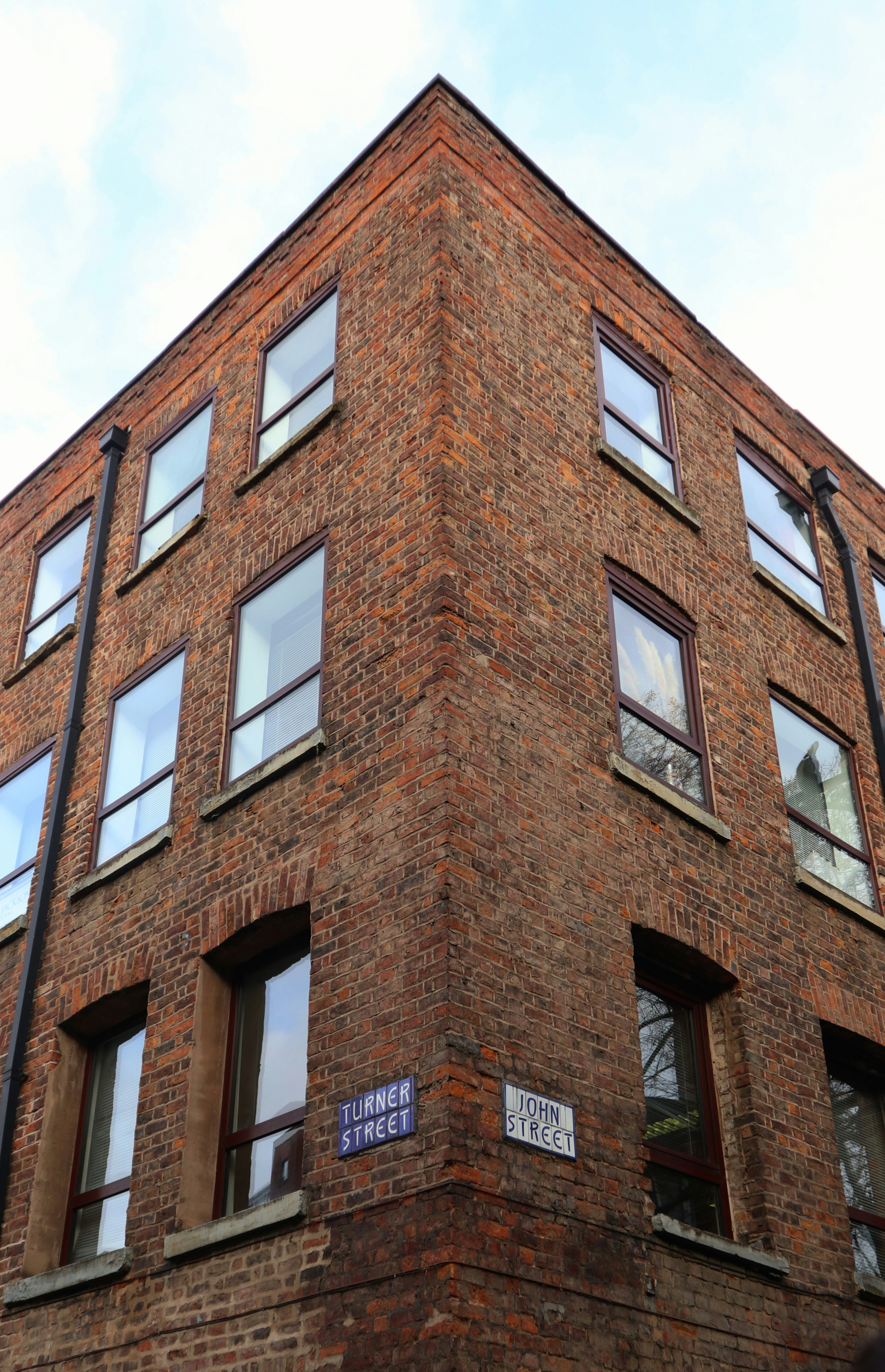 low-angle photography of brown high-riser building under blue and white sky during daytime