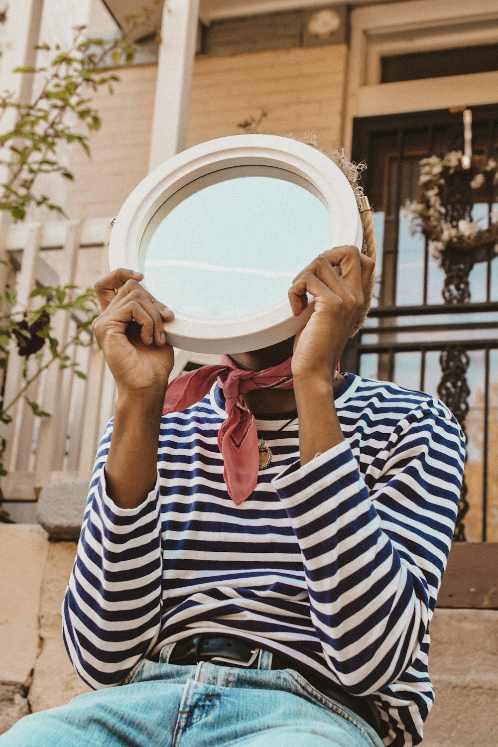 person in striped shirt holding round mirror